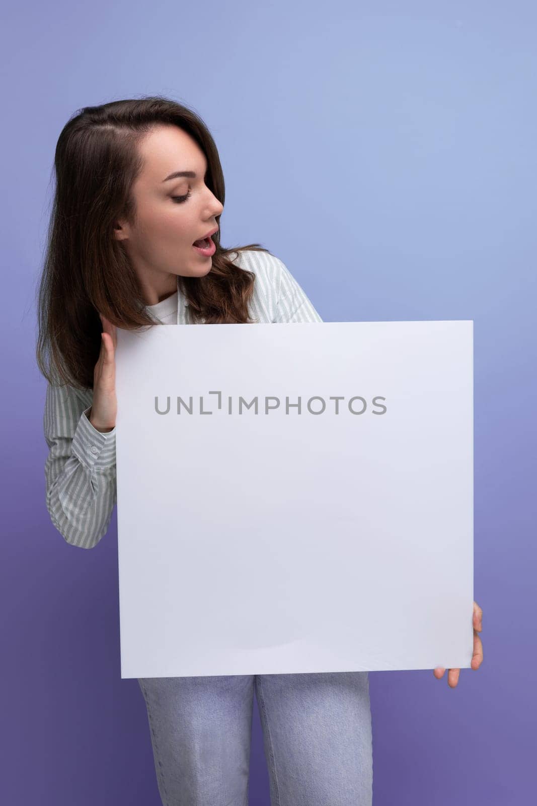 pretty brunette young business woman in a shirt demonstrates a white poster with a mockup.