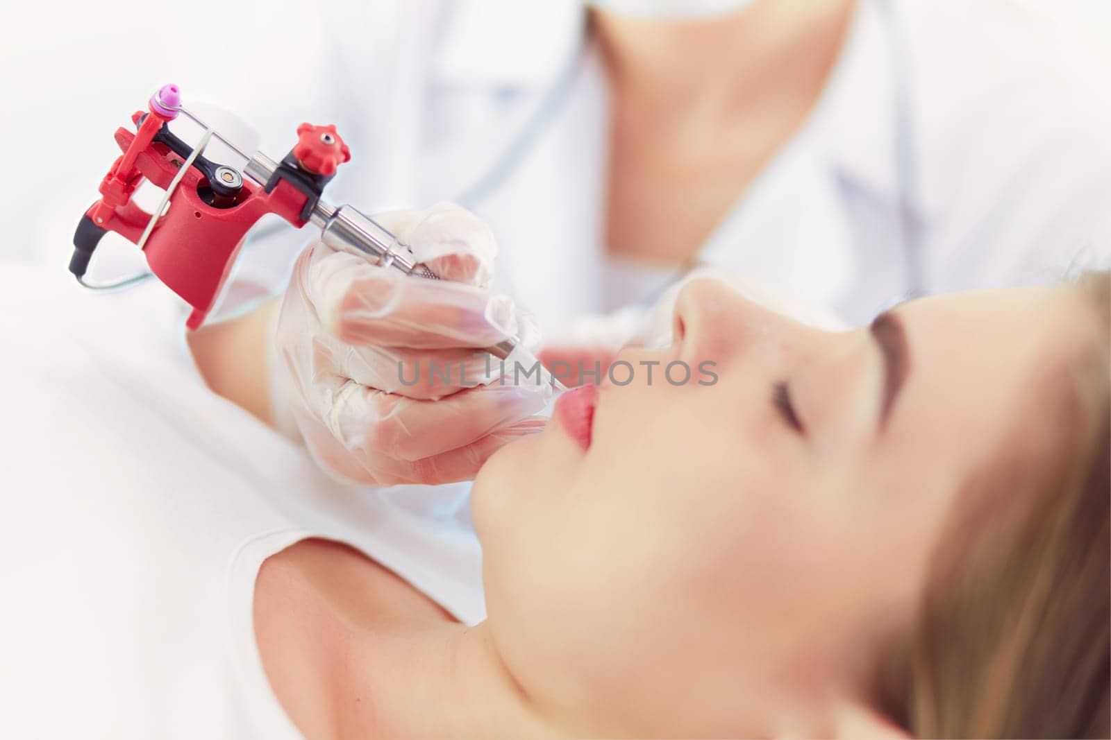 A young girl having red lips permanent makeup, micropigmentation.