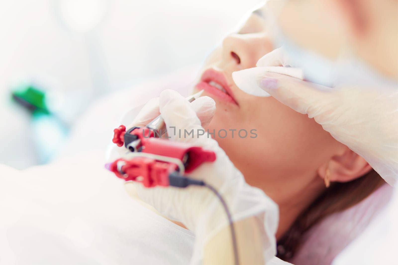 A young girl having red lips permanent makeup, micropigmentation.