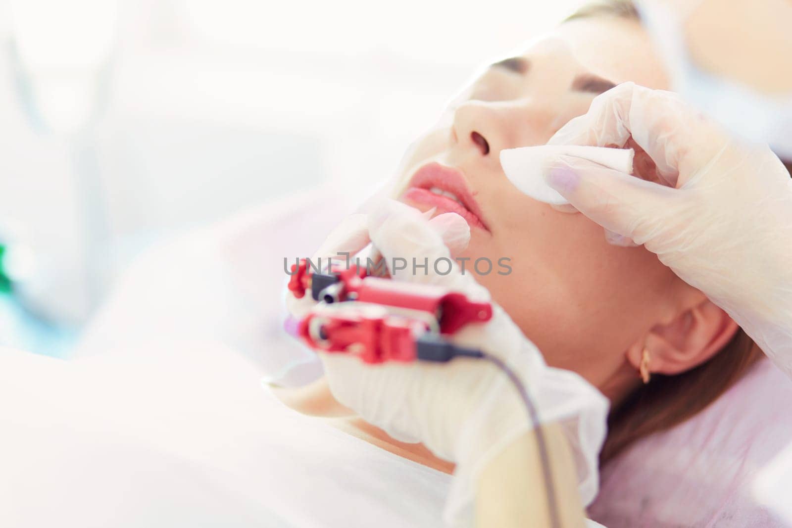A young girl having red lips permanent makeup, micropigmentation.