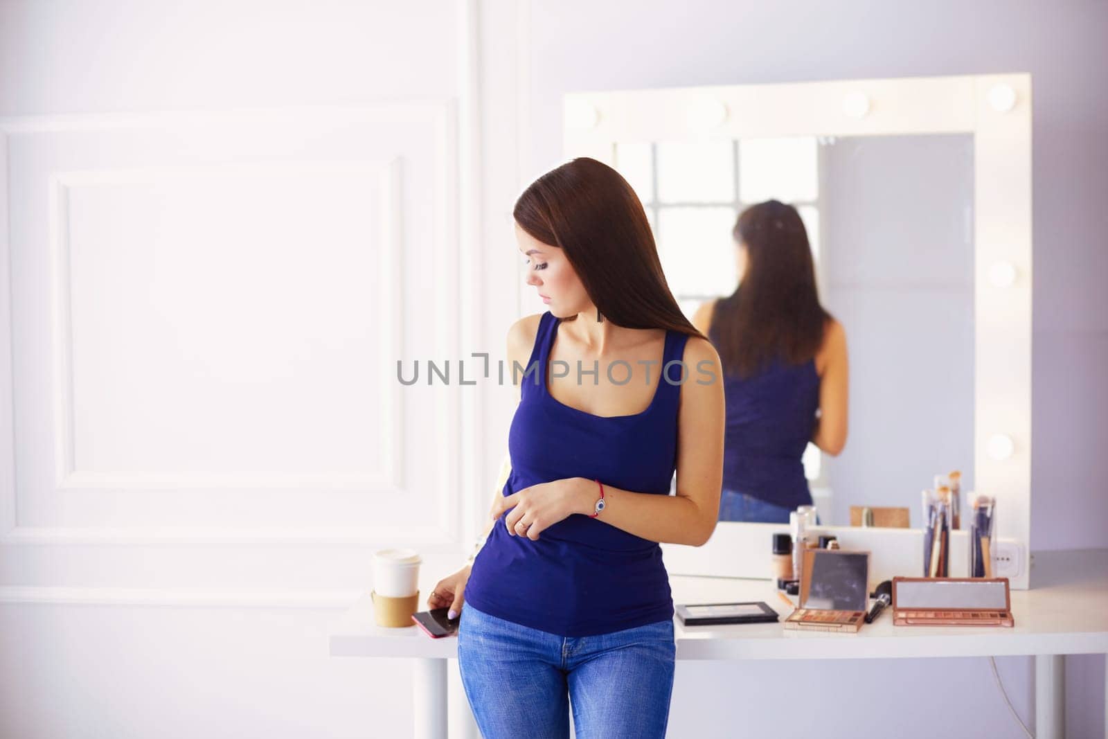 Woman standing with hands folded in her salon.