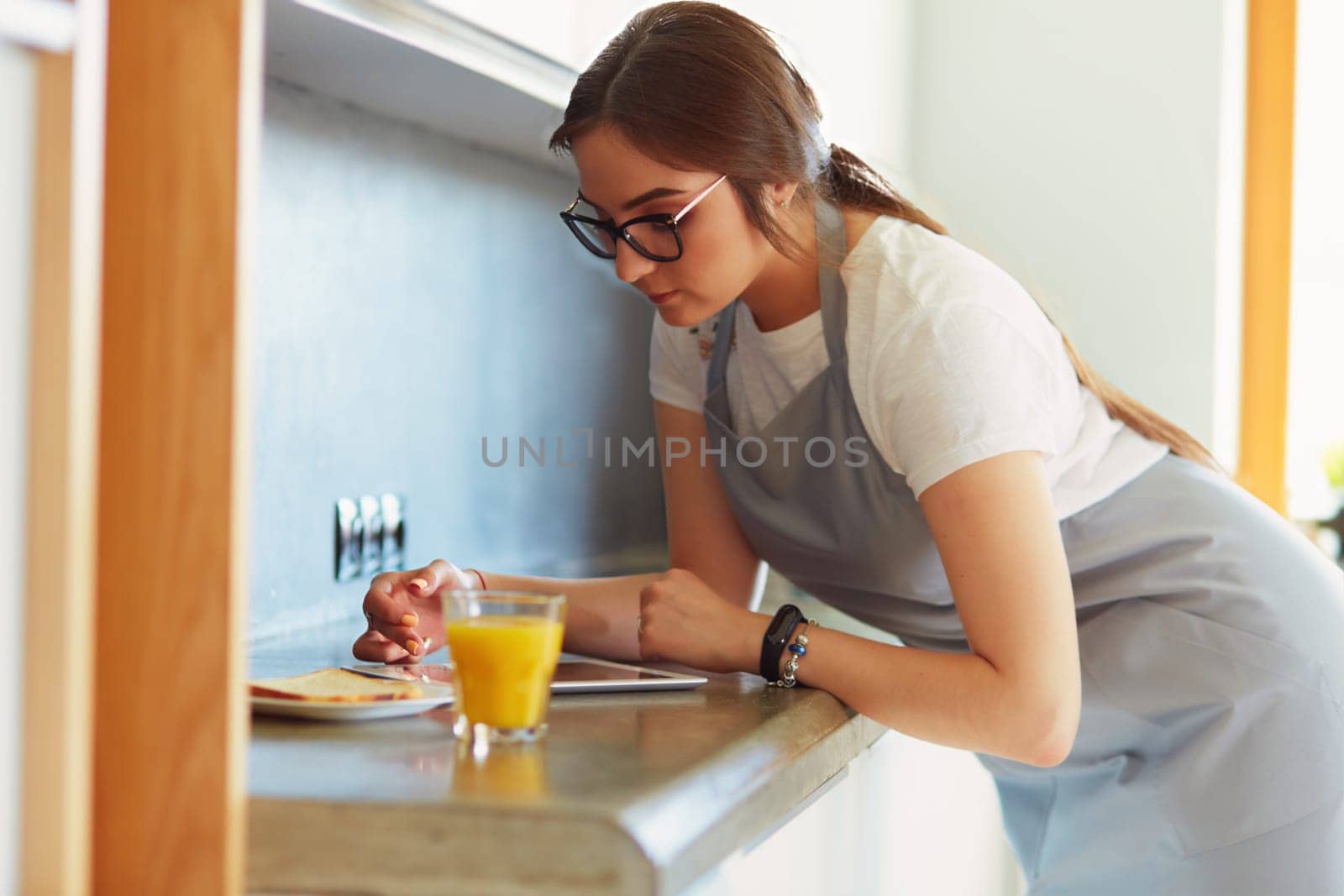 Portrait of young attractive caucasian brunette housewife at kitchen. Morning with cup of coffee and tablet pc.