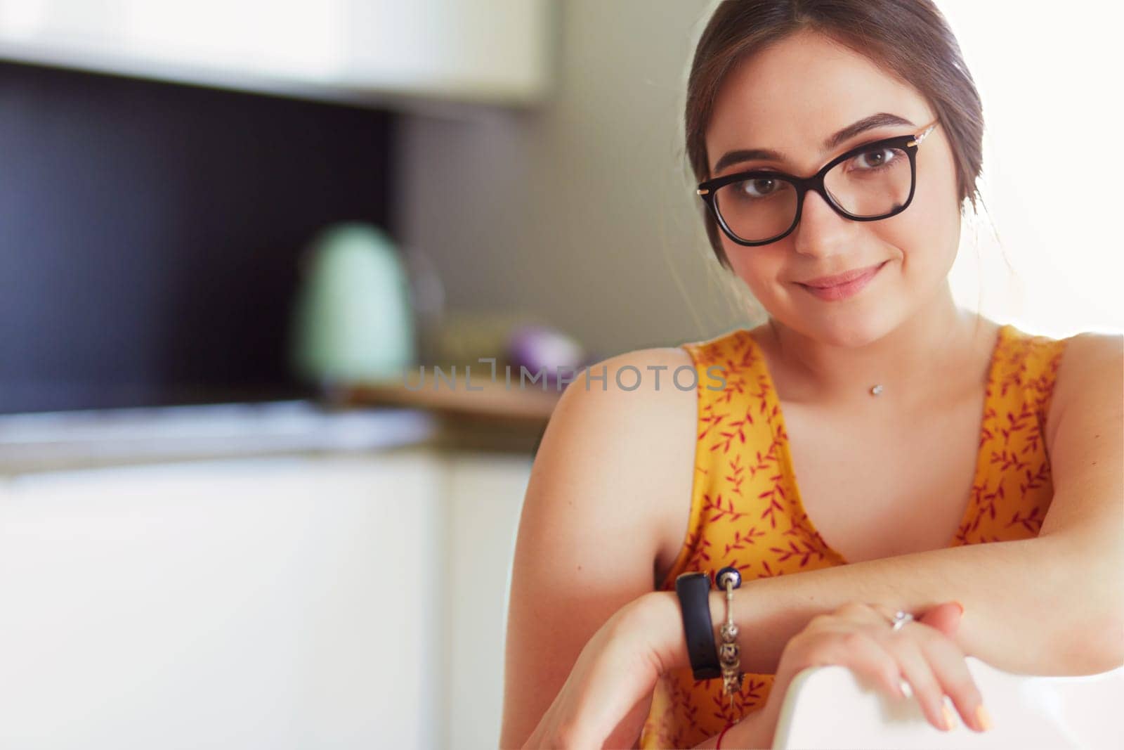 Young woman sitting a table in the kitchen .