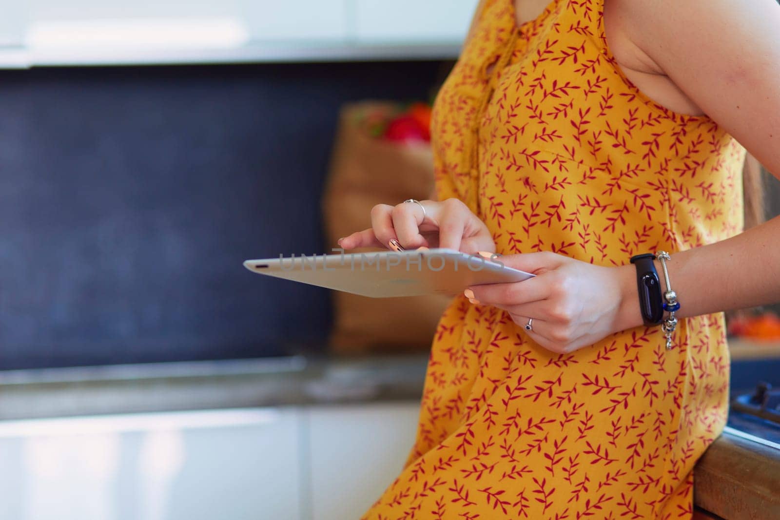 Portrait of young attractive caucasian brunette housewife at kitchen. Morning with cup of coffee and tablet pc.