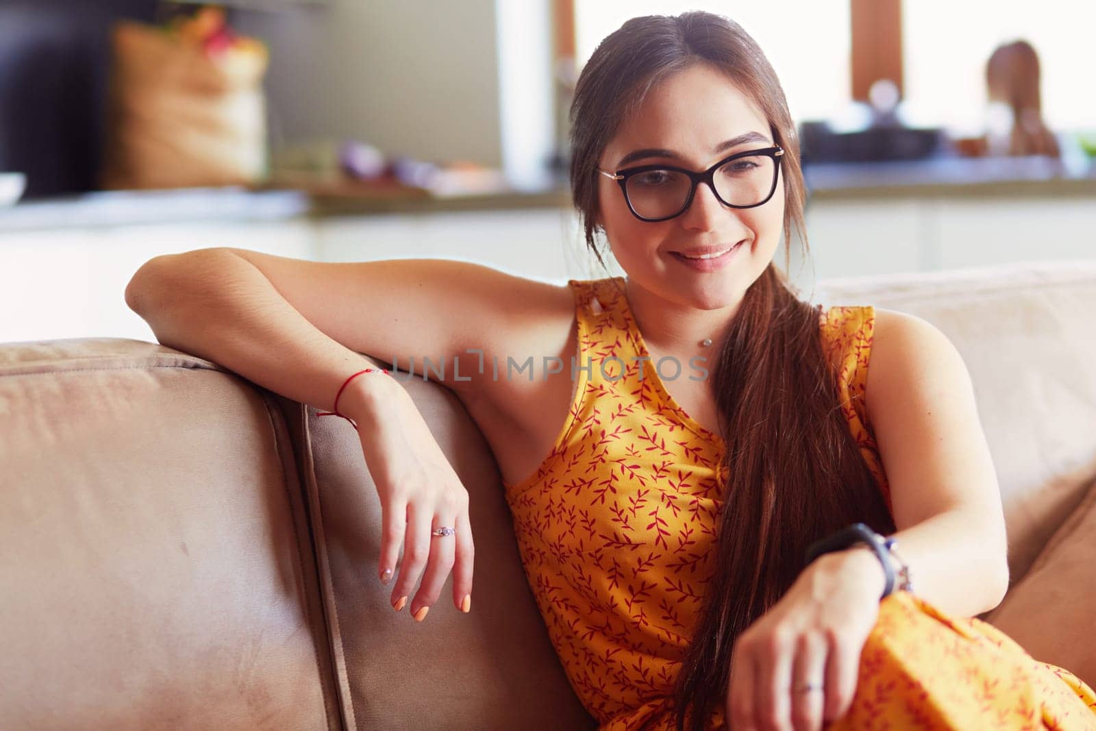 Portrait of smiling woman sitting on sofa. Casual style indoor shoot.