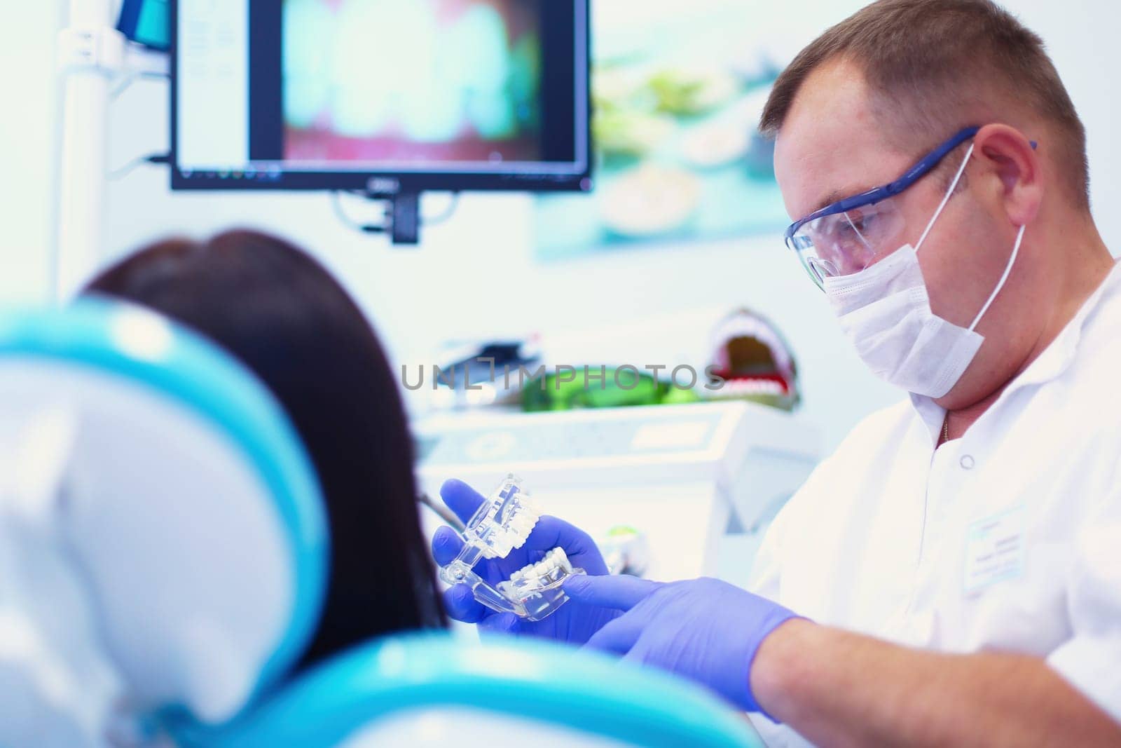 Portrait of a dentist who treats teeth of young woman patient.