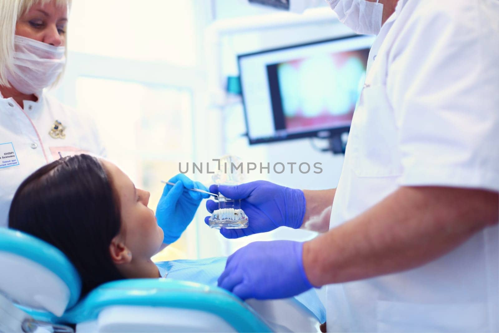 Portrait of a dentist who treats teeth of young woman patient.