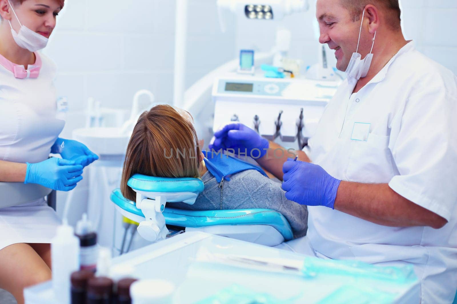 Senior male dentist in dental office talking with female patient and preparing for treatment.