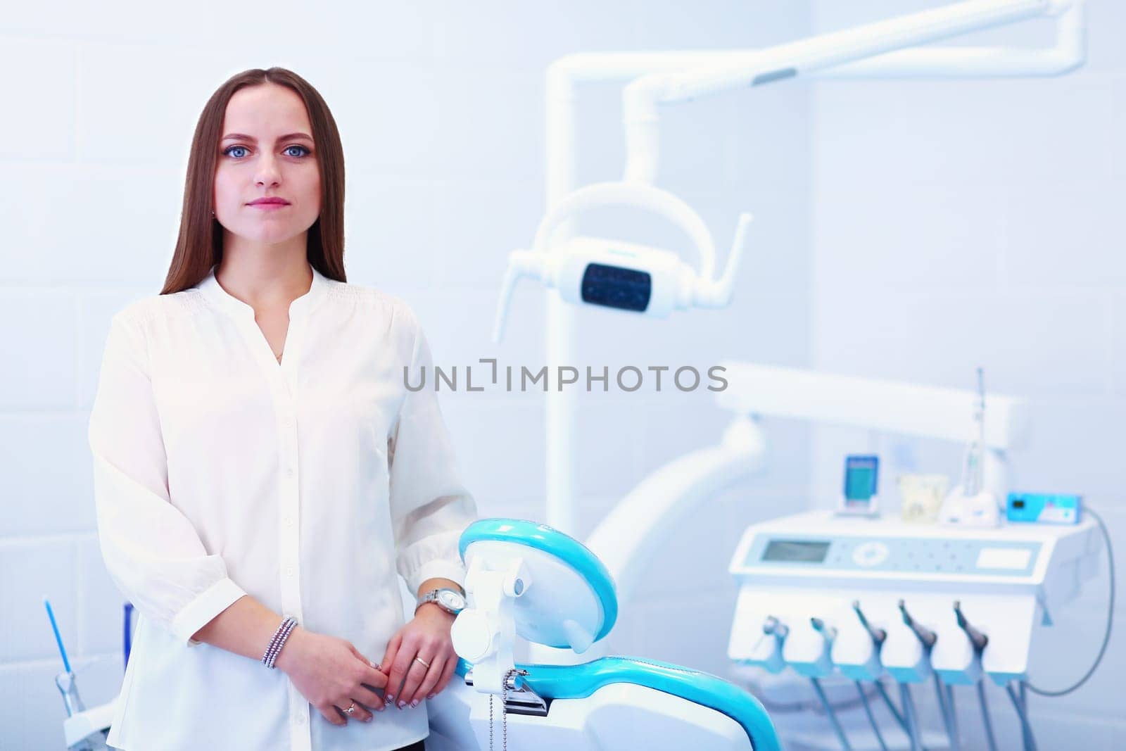 Woman dentist standing in her office smiling by lenets