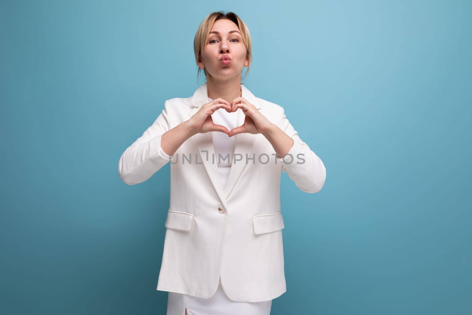 pretty friendly blond young business woman in white jacket and skirt smiling.