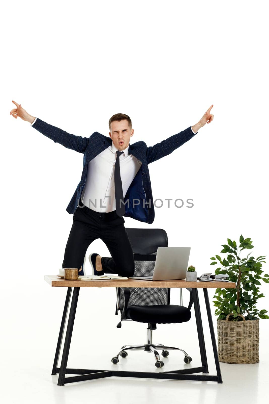 Satisfied young businessman gesturing emotionally and celebrating victory in the office