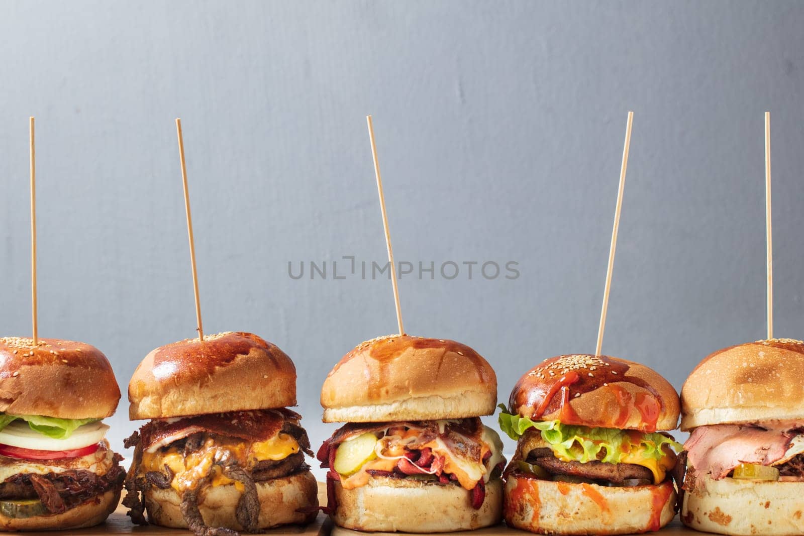 Many different burgers with ingredients on a wood plate. High quality photo