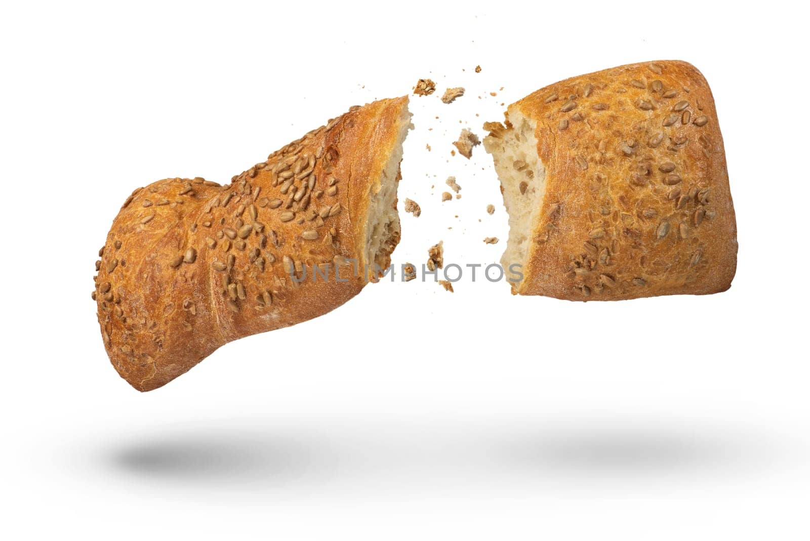 Loaf of crispy bread isolated on white. A loaf of freshly baked crispy bread is broken in half with crumbs flying in all directions at the break. Fresh baking concept. Top view. by SERSOL