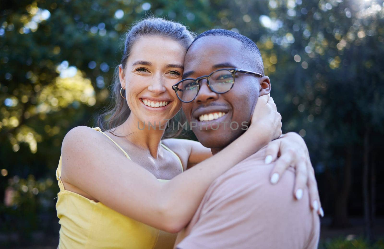 Portrait, couple on a date and hug with love in nature, outdoor in park with commitment in interracial relationship. Trust, support and happy people, black man and woman smile on face with fresh air.