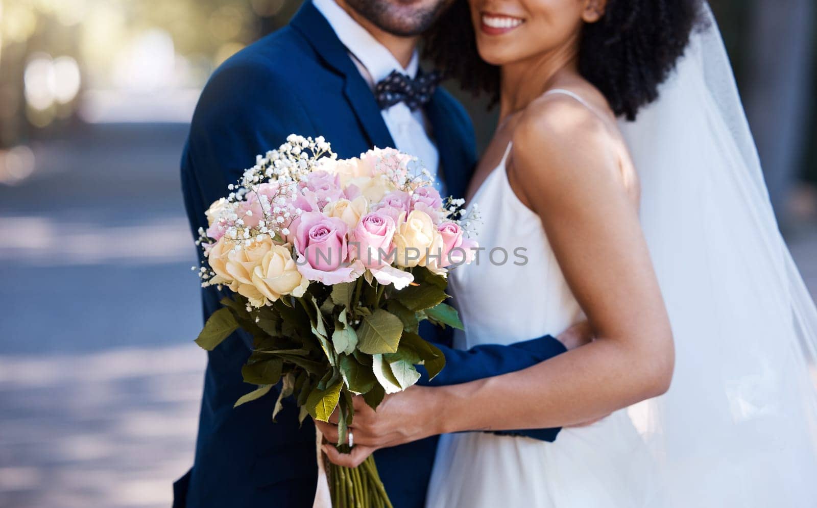 Flowers, wedding and marriage with a bride and groom posing outdoor for a photograph at their celebration event or ceremony. Rose bouquet, love and romance with a newlywed black couple outside by YuriArcurs