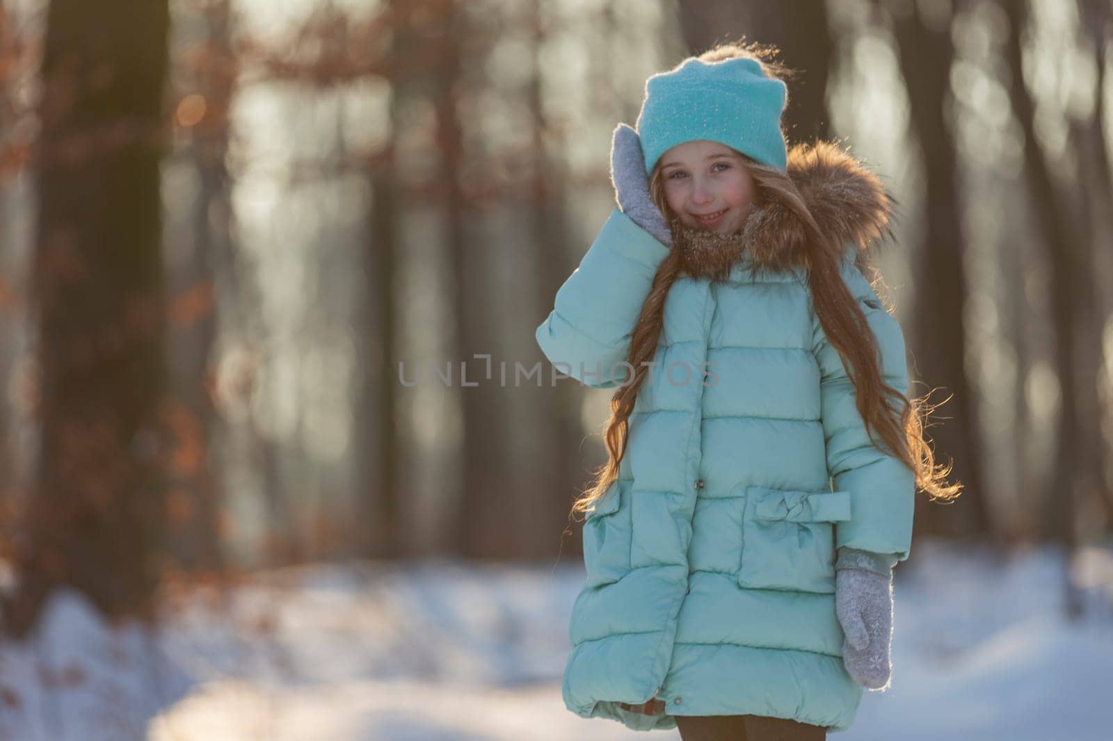 portrait of a girl against the backdrop of a winter forest illuminated by the sun