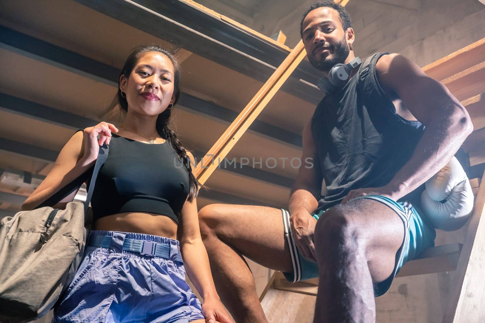 Portrait of a young fitness couple in warehouse looking at camera. Sport exercise concept. by PaulCarr