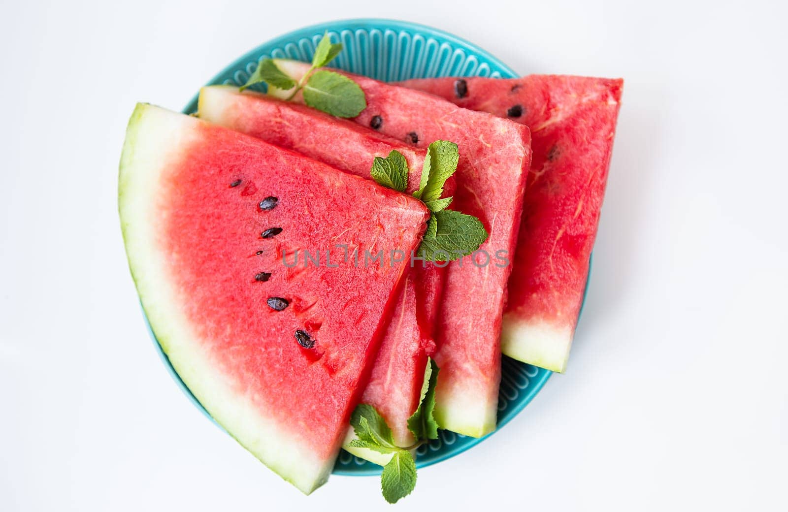 Fresh ripe slices of watermelon along with mint leaves lie on a plate on the table. Tasty and healthy, summer food. by sfinks