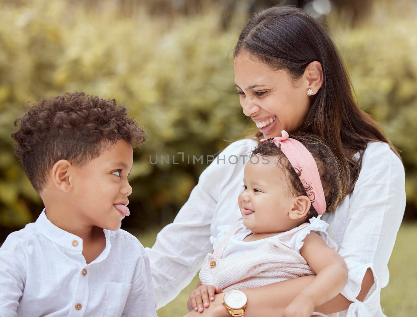 Family, happy and children with a mother having fun with tongue out gesture in a nature park. Kids, comic and funny quality time of a mom, boy and baby together with happiness, love and youth.