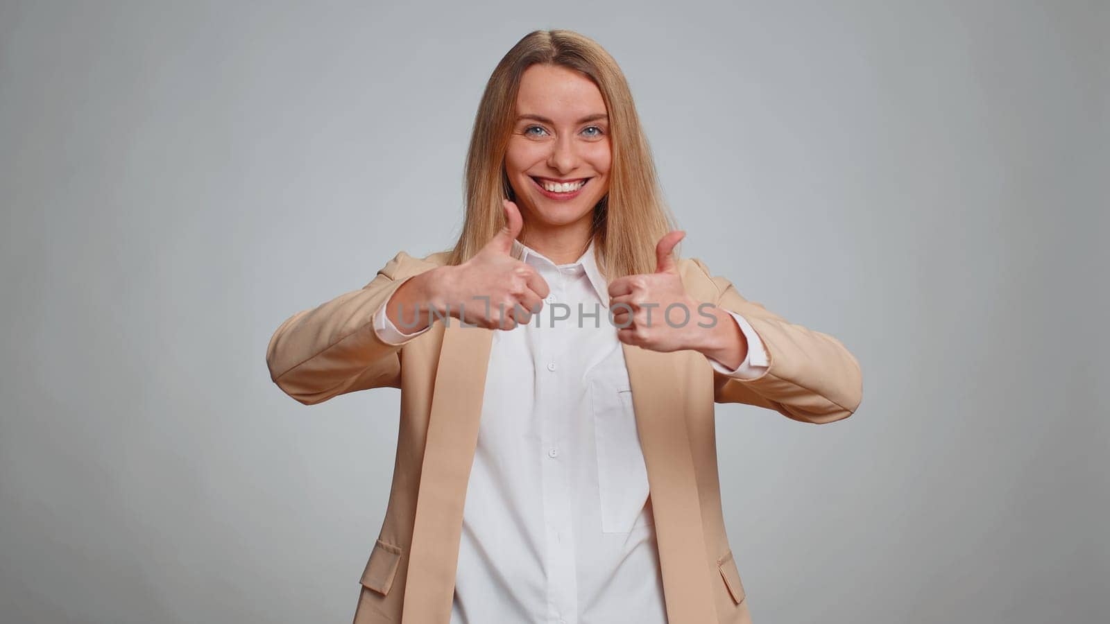 Like. Portrait of secretary woman in suit raises thumbs up agrees with something or gives positive reply recommends advertisement likes good. Business girl isolated alone on gray studio background