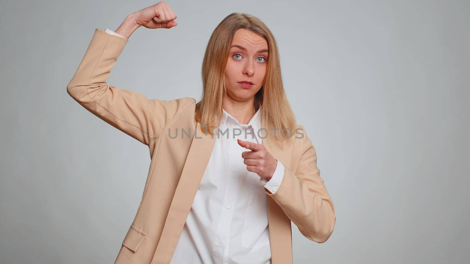 I am strong and independent. Business woman showing biceps and looking confident, feeling power strength to fight for rights, energy to gain success win. Entrepreneur girl on gray studio background