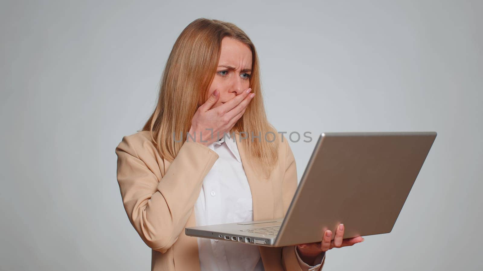 Portrait of young businesswoman use laptop typing browsing working, loses becoming surprised sudden lottery results, bad news, fortune loss, fail. Female girl in formal suit. Woman on gray background