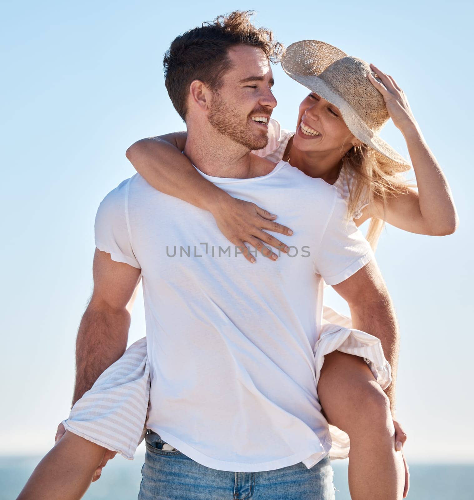 Piggy back, love and couple at a beach for a happy anniversary vacation or honeymoon holiday adventure. Smile, romance and healthy woman enjoys quality time or bonding with a romantic partner at sea.