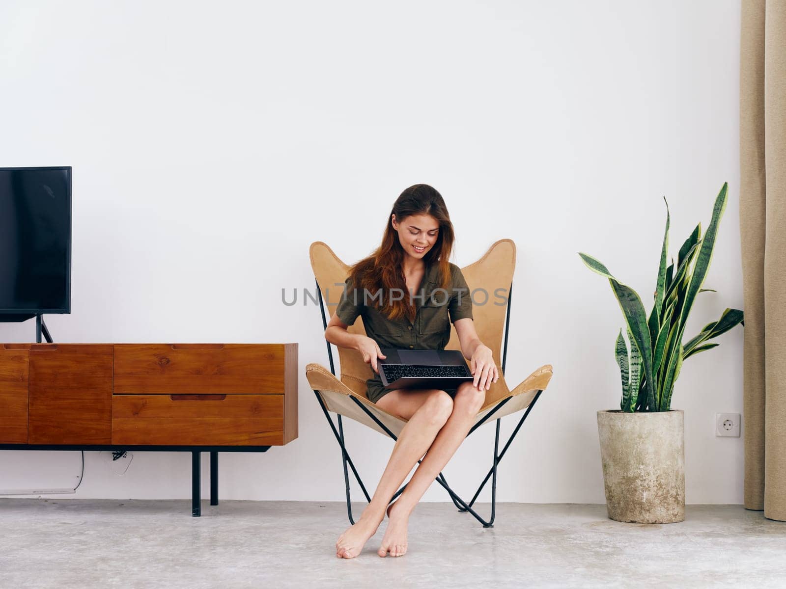 Woman student study sits on a chair with a laptop work at home smile, modern stylish interior Scandinavian lifestyle, copy space. High quality photo
