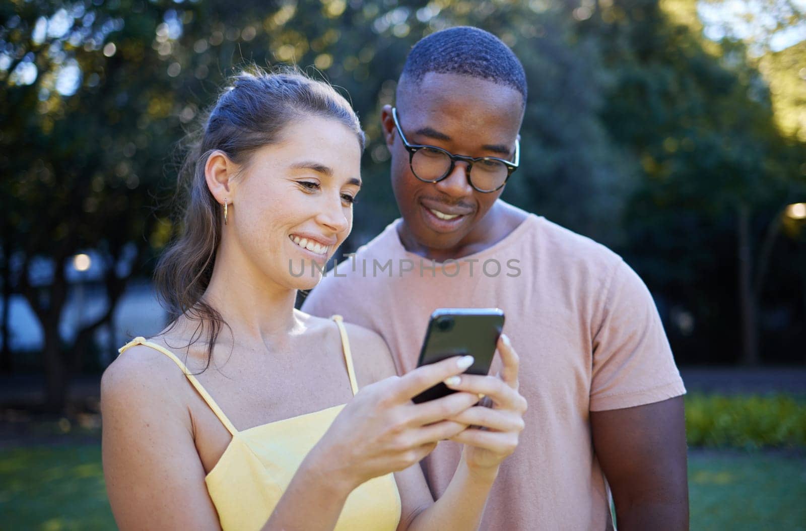 Interracial, meme and couple with a phone in a park, funny communication and laughing at social media. Comic, streaming and black man and woman reading a joke on a mobile in nature of France.