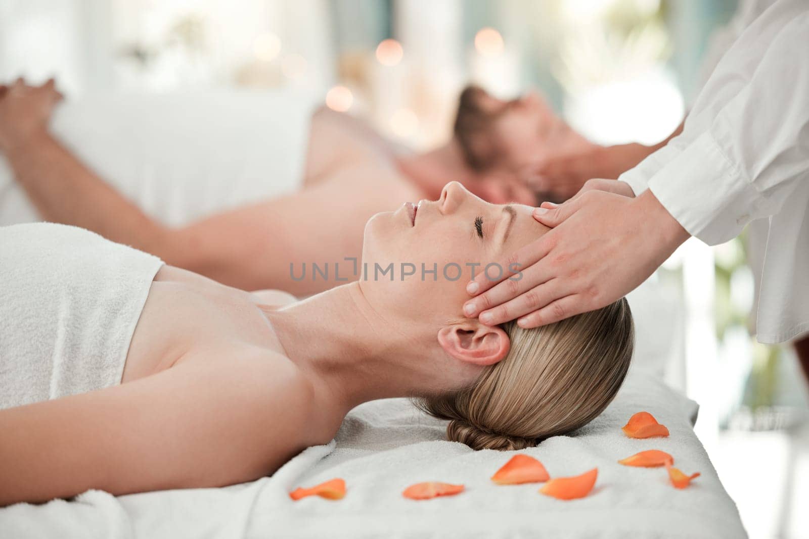 Woman, spa and massage on head while on bed with flowers for relax, wellness and calm on vacation. Luxury, health and physical therapy for couple at hotel, salon and hands on scalp for natural care by YuriArcurs