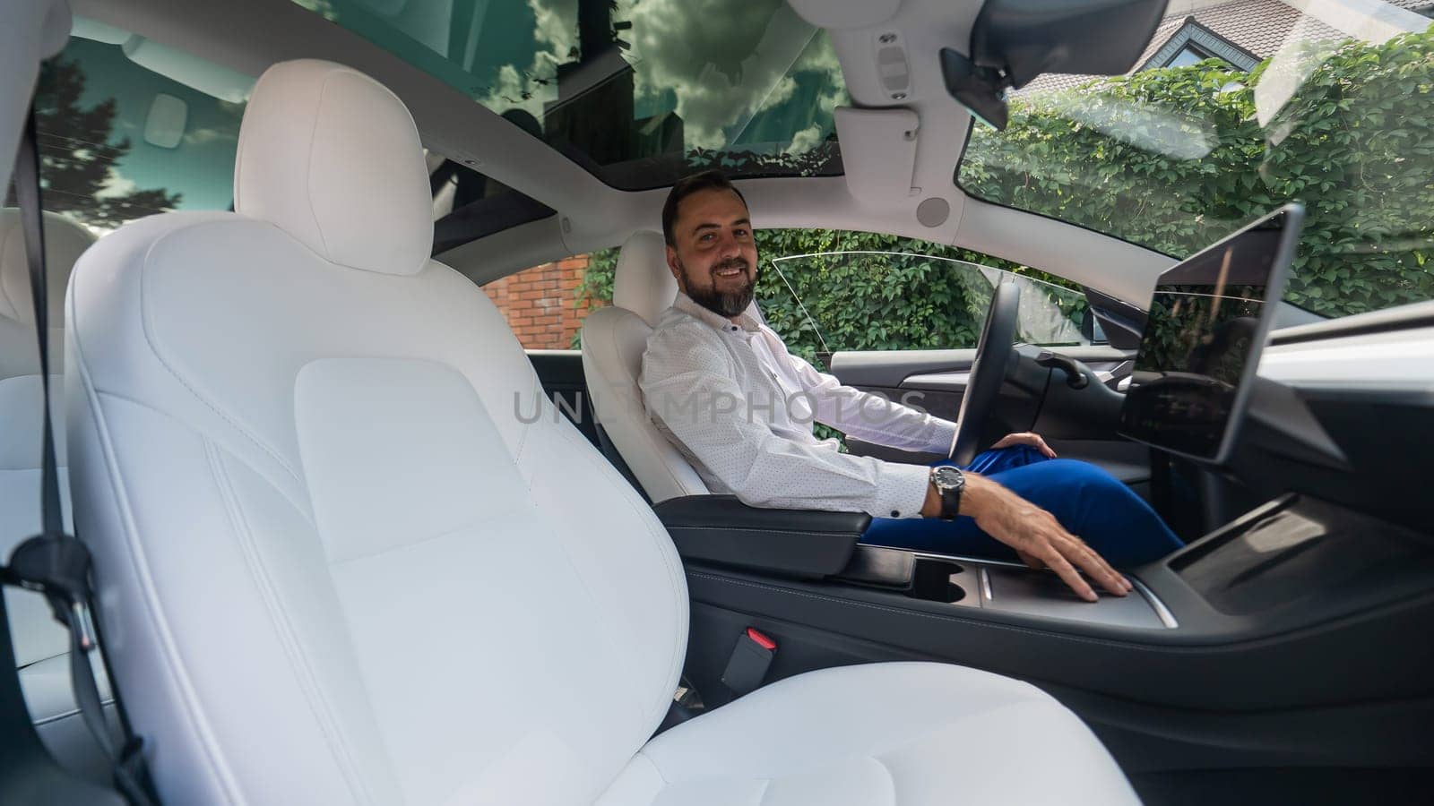 Caucasian bearded man in a suit driving a car