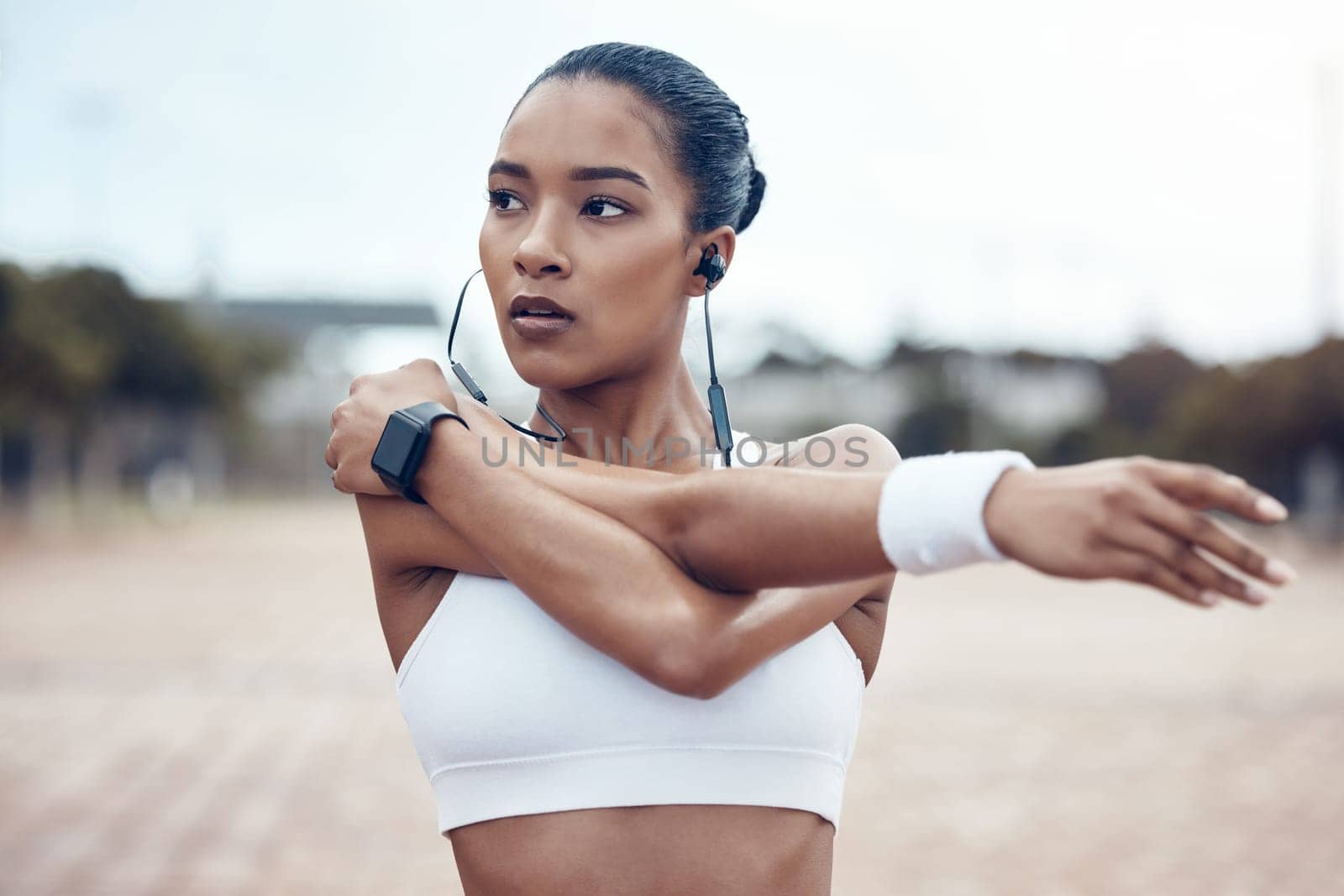 Black woman, fitness and stretching, exercise and earphones, music and motivation for active lifestyle outdoors. African American, strong and focus, cardio and endurance, workout and healthy living. by YuriArcurs