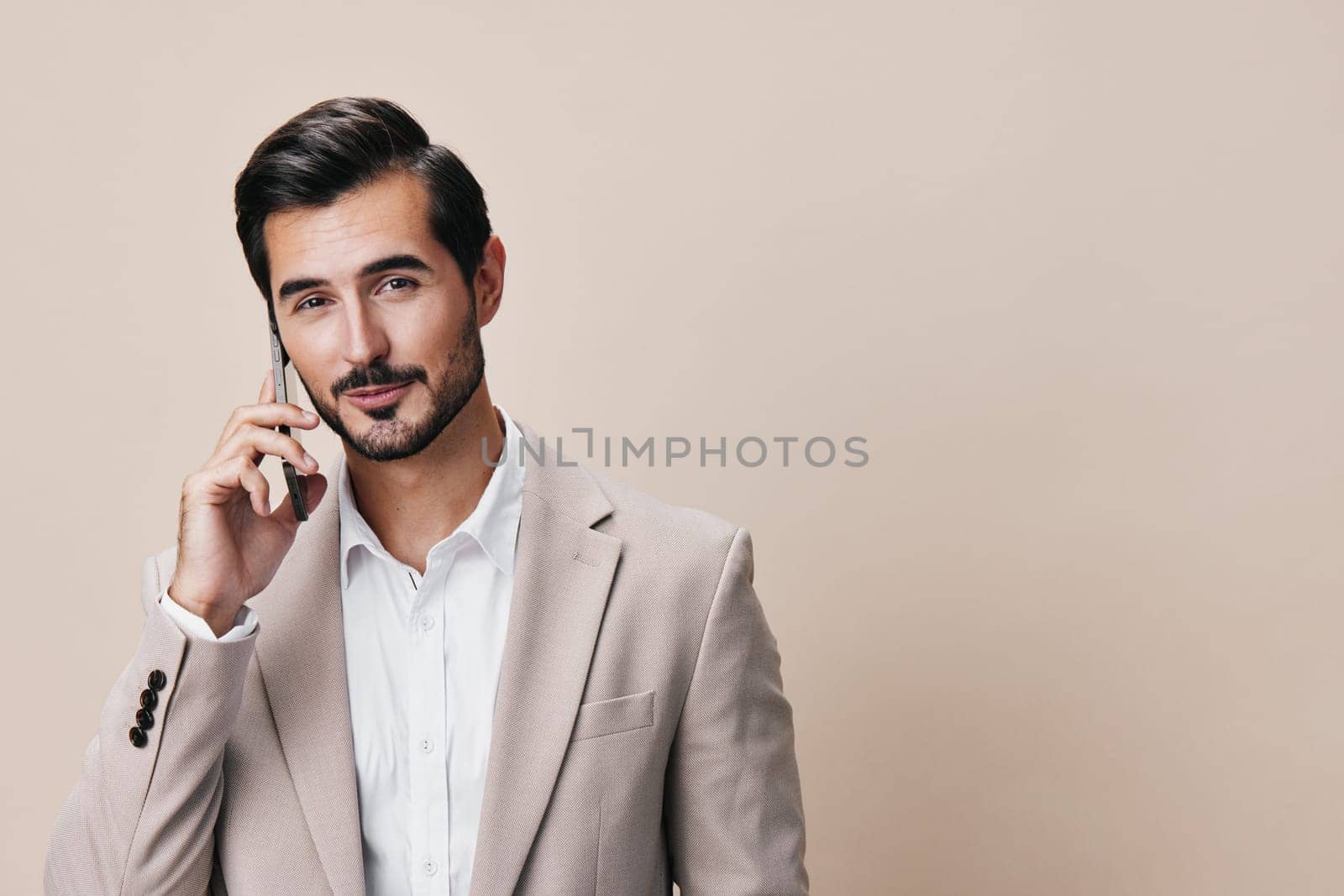 beard man suit lifestyle smile guy app confident phone smartphone adult hold portrait business businessman happy message beige technology call studio