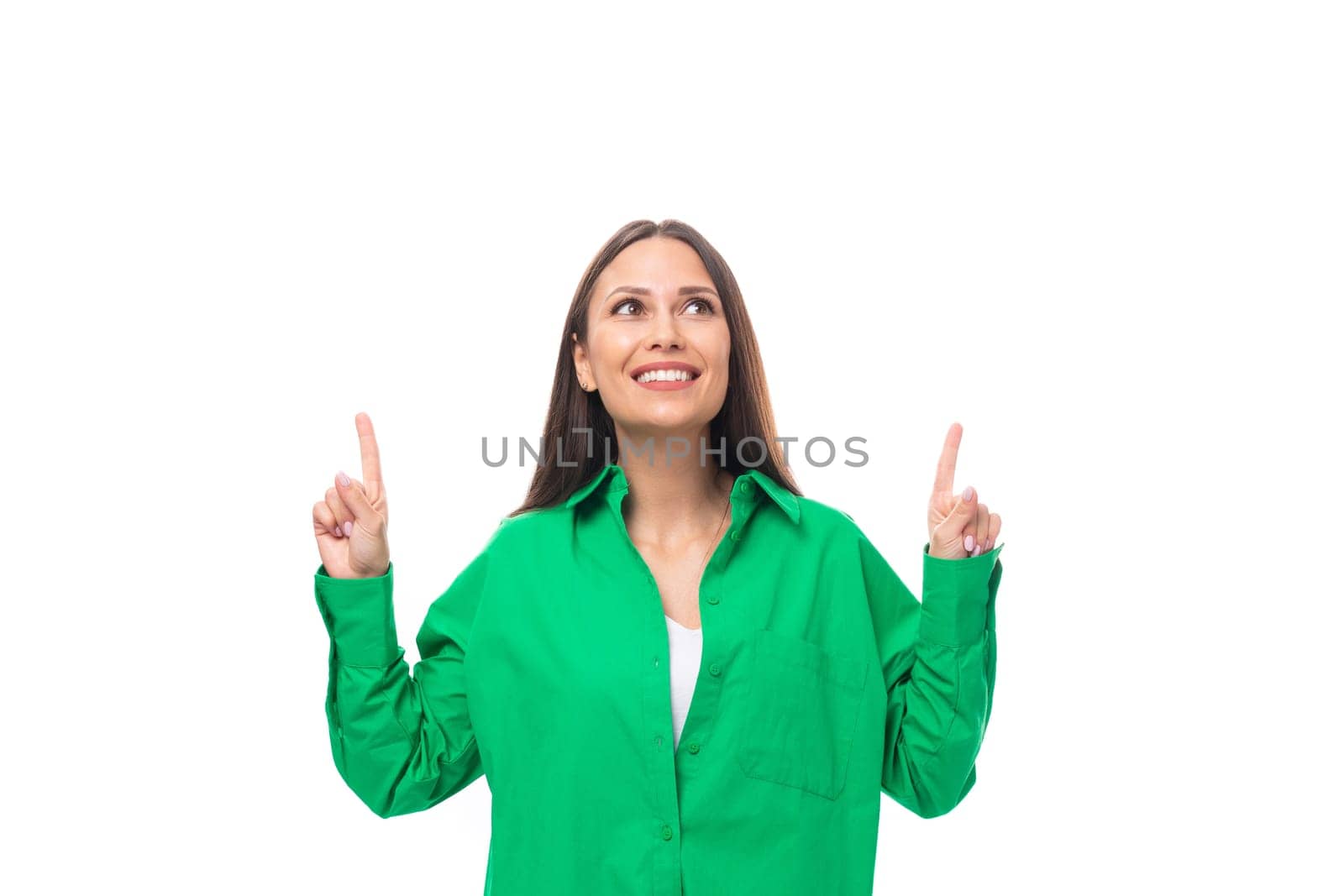 pretty slender european brunette woman with long hair and brown eyes dressed in a casual green shirt looks at the empty space from above.