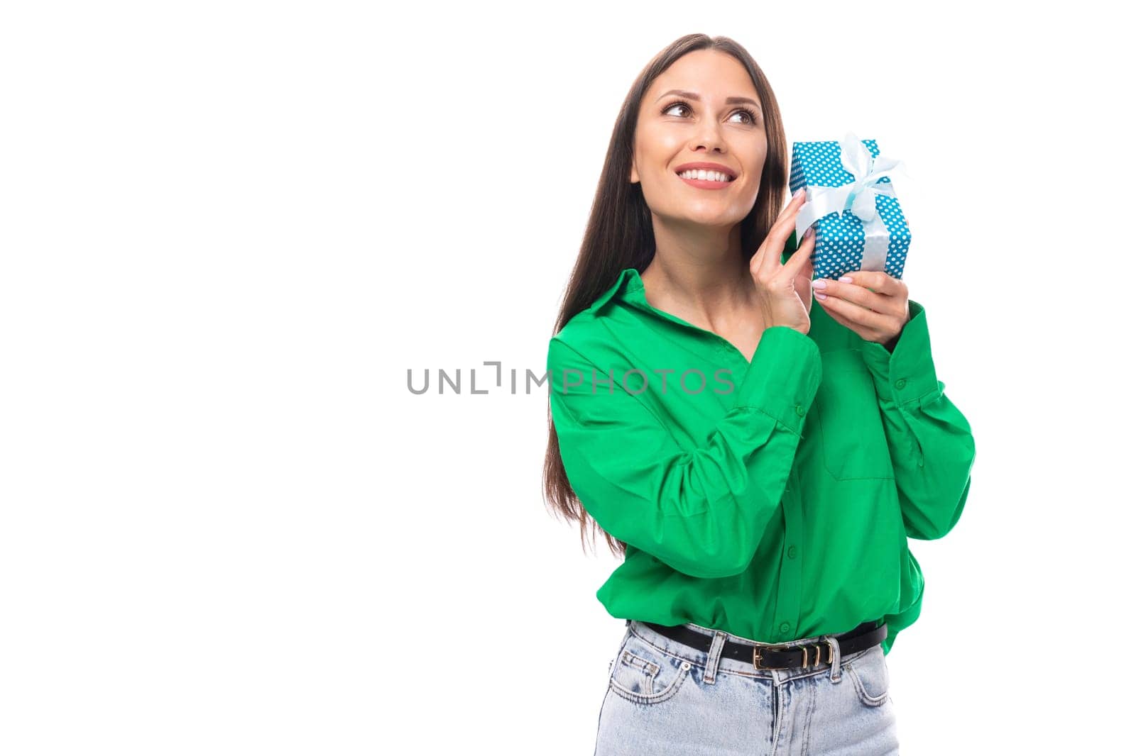 brown-eyed brunette young business lady in a green shirt holds a gift for the holiday.