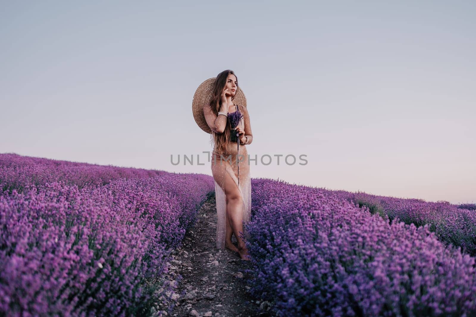 Woman lavender field. Happy carefree woman in beige dress and hat with large brim smelling a blooming lavender on sunset. Perfect for inspirational and warm concepts in travel and wanderlust. Close up by panophotograph