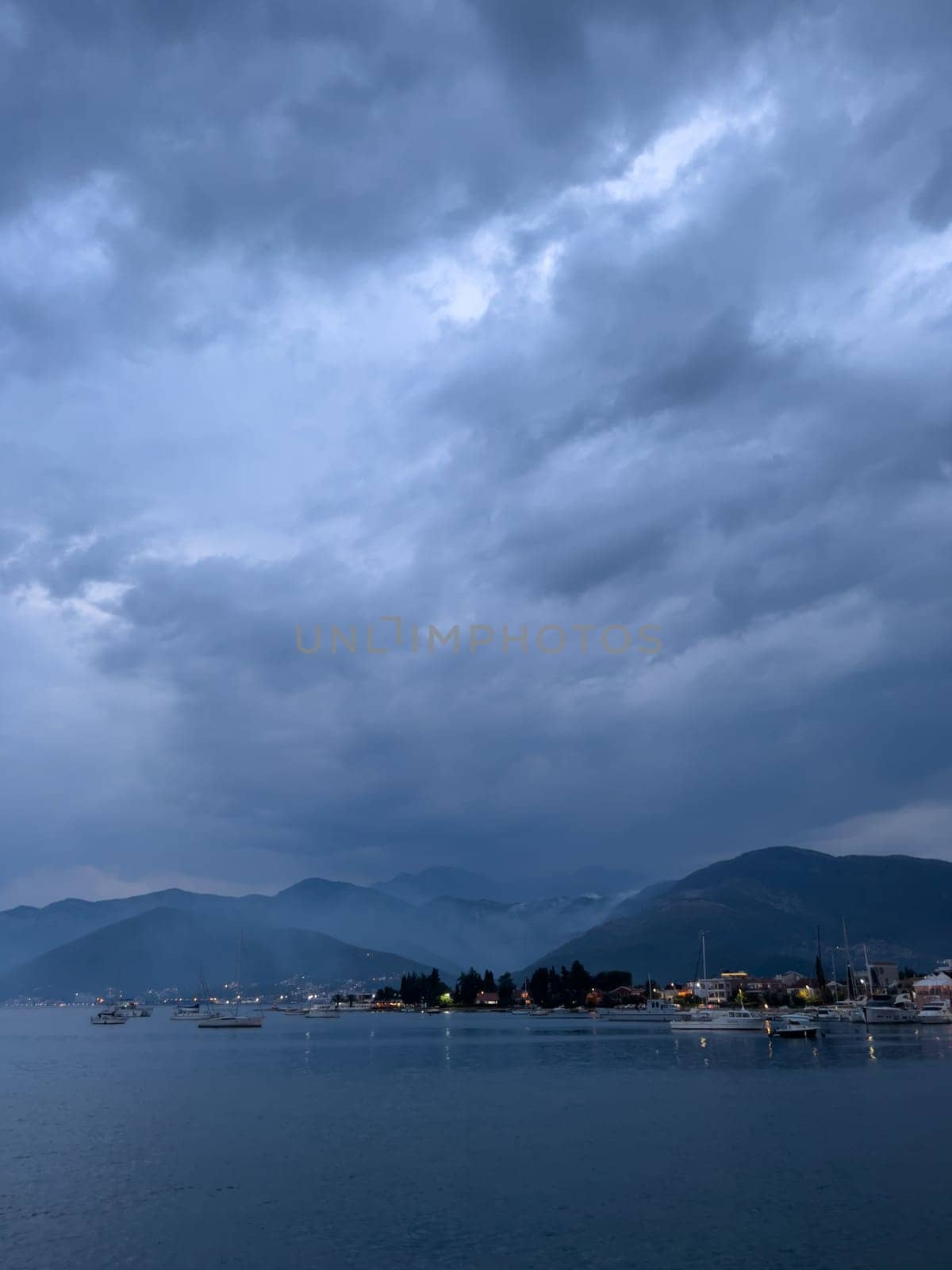 Falling dusk on a bay with sailing yachts at the foot of a mountain range. High quality photo