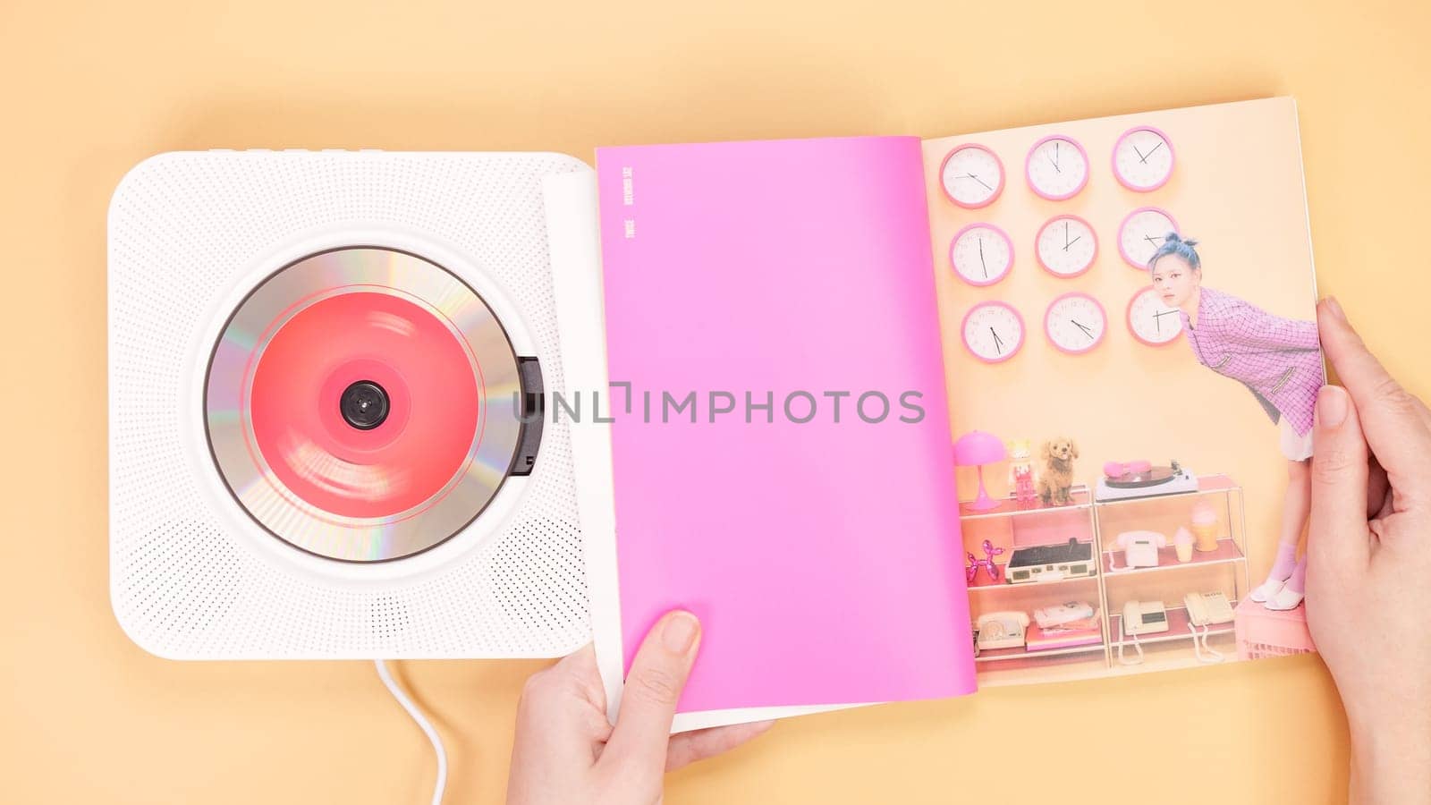 Hands holding Twice Between 1 and 2 mini Album photobook on yellow. Music CD player. South Korean girl group Twice. Space for text. Gatineau, QC Canada - December 27 2022