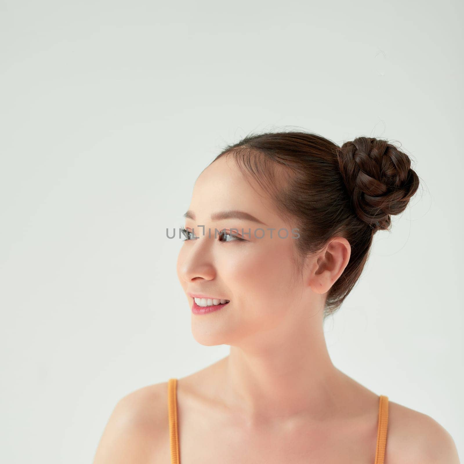 Modern playful girl with two hair buns smiling looking up dreamily. 