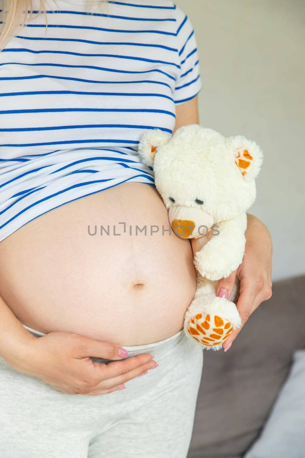 Pregnant woman and white teddy bear. Selective focus. Cute.