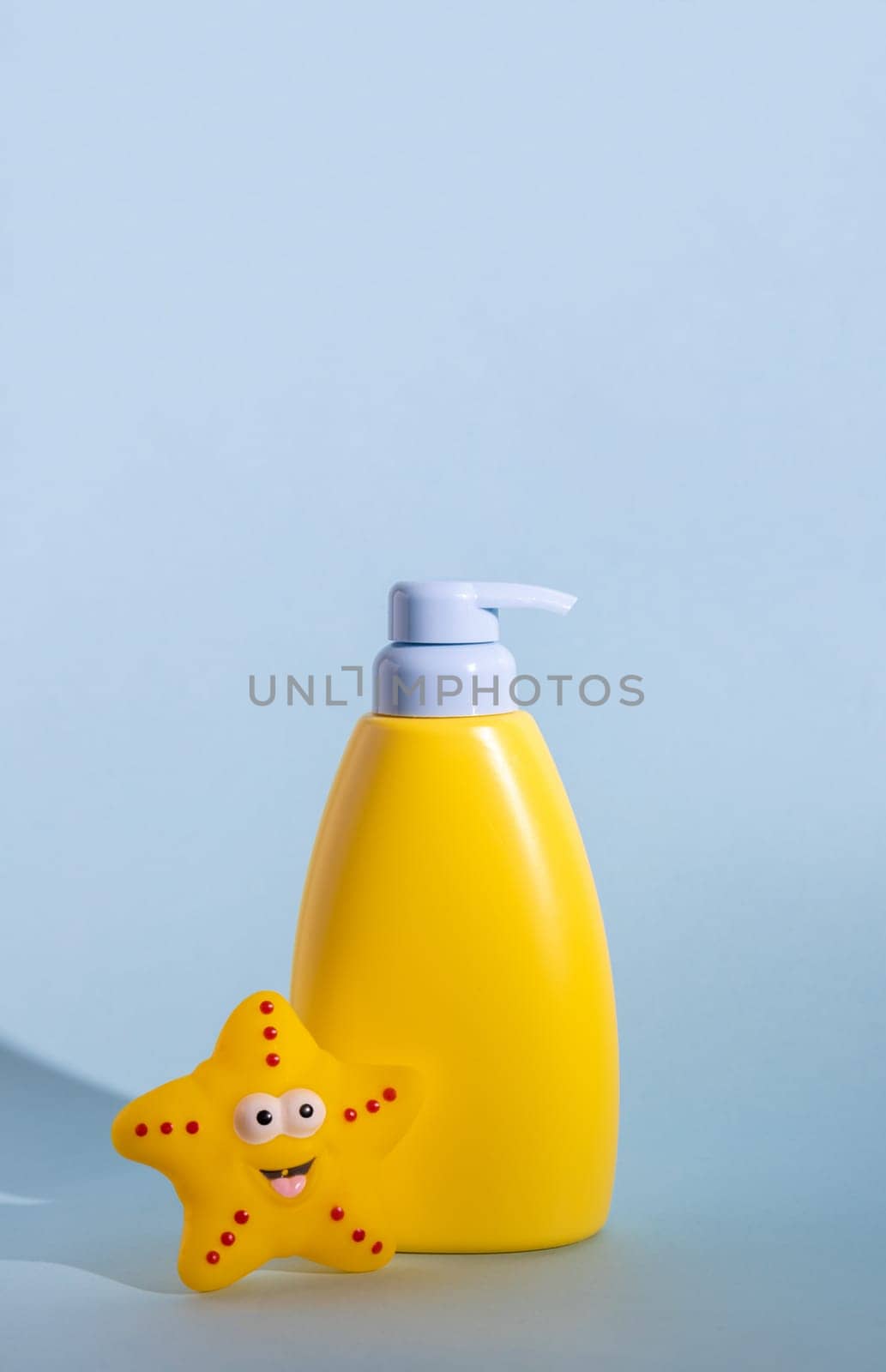 Yellow layout of a children's cosmetic product with a place for a logo and funny rubber toy. Baby sun protection, sunscreen or body lotion. Space for text. Summer protection concept