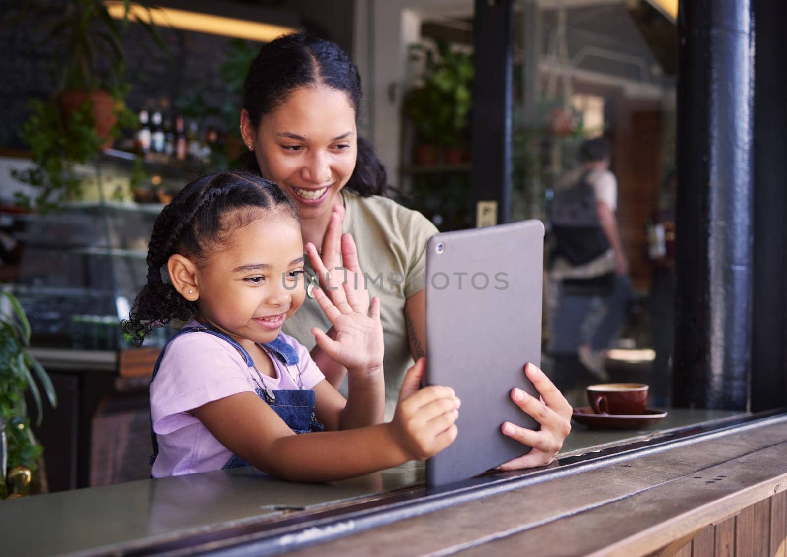 Video call, restaurant and woman and girl with a tablet waving on social media, online and app at a coffee shop. Kid, daughter and child with parent on the internet for communication and talking.