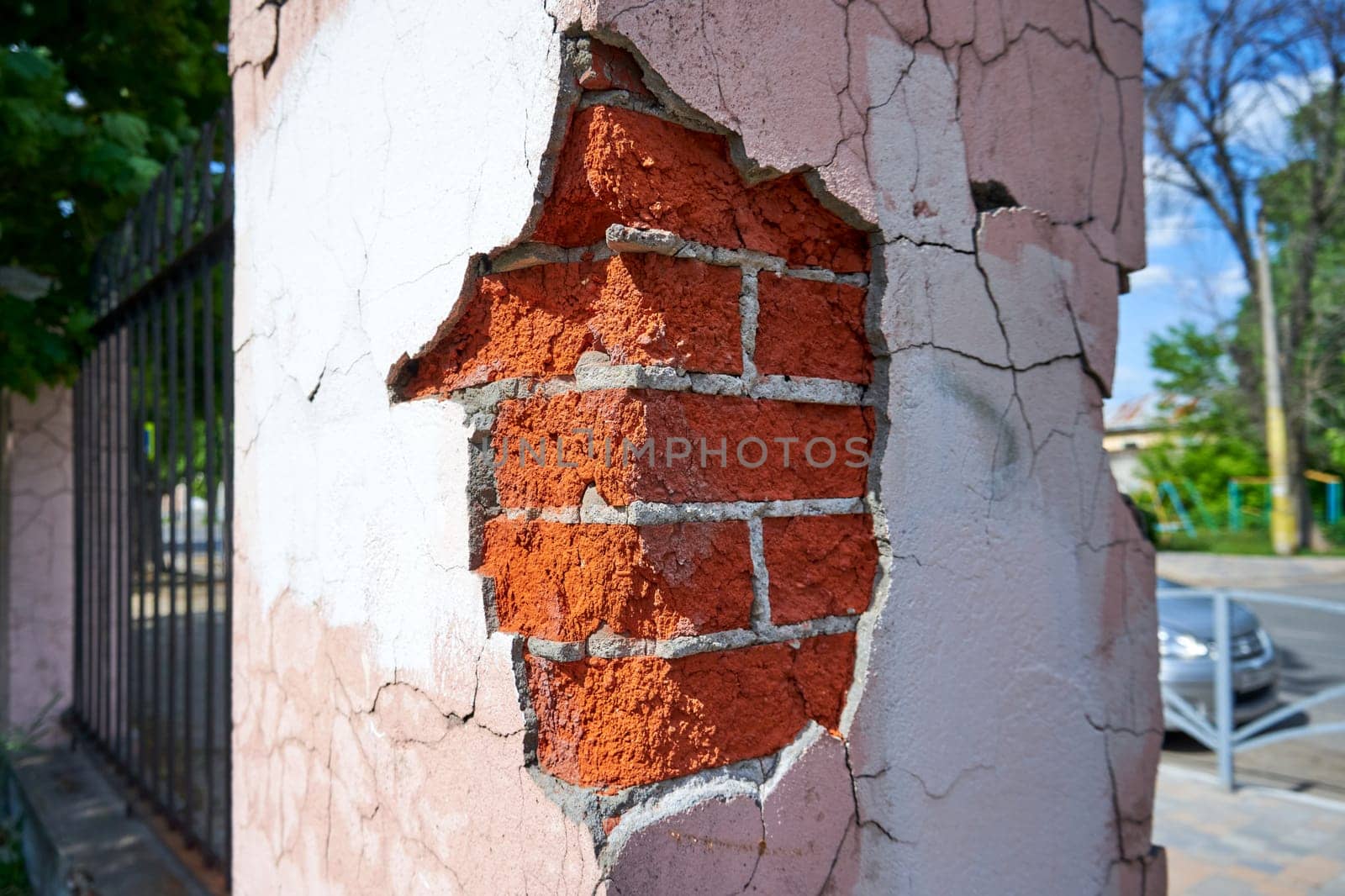 Close-up corner of a brick fence with crumbling plaster