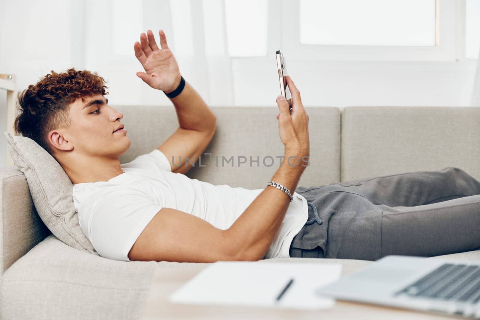 man interior sitting using laptop lifestyle phone couch person teenager home mockup internet male holding text message online technology