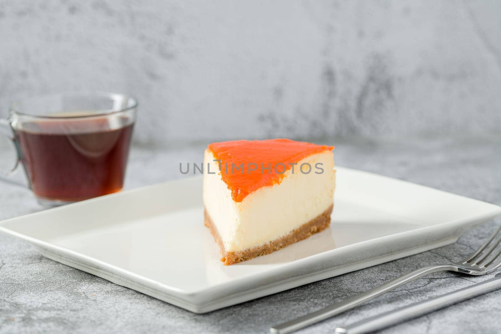 Pumpkin cheesecake on porcelain plate with tea on stone table