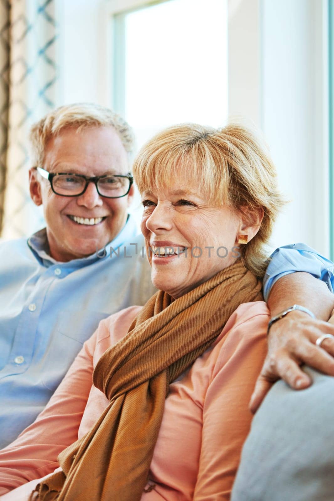 Relaxing together is their favorite thing to do. a mature couple relaxing together on the sofa at home. by YuriArcurs