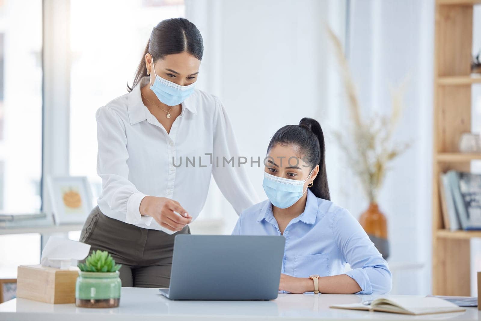 Covid, training and employees talking with laptop in an office together at work. Corporate workers speaking about strategy for business, reading email and working on a proposal on a pc with face mask.