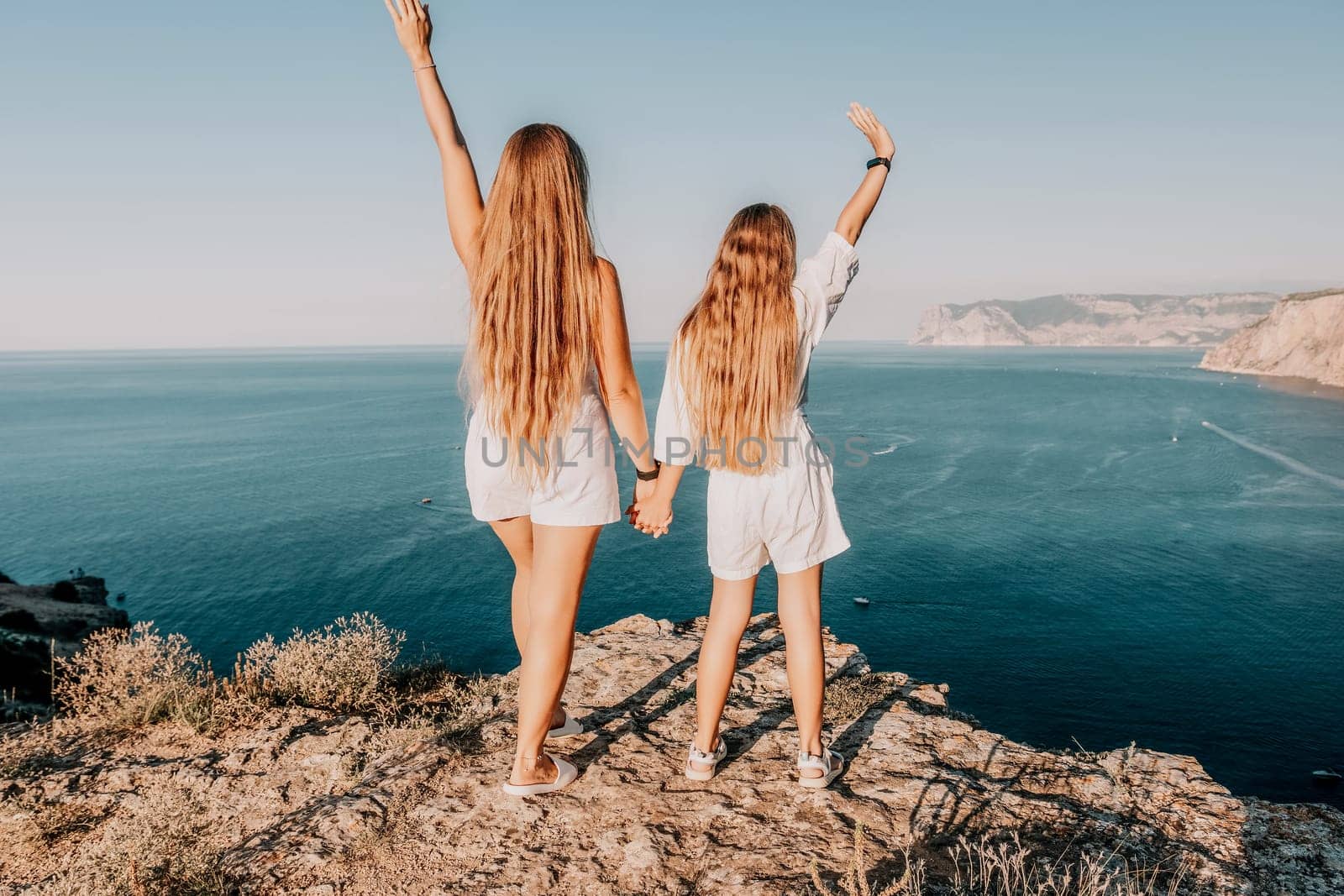 Close up portrait of mom and her teenage daughter hugging and smiling together over sunset sea view. Beautiful woman relaxing with her child.