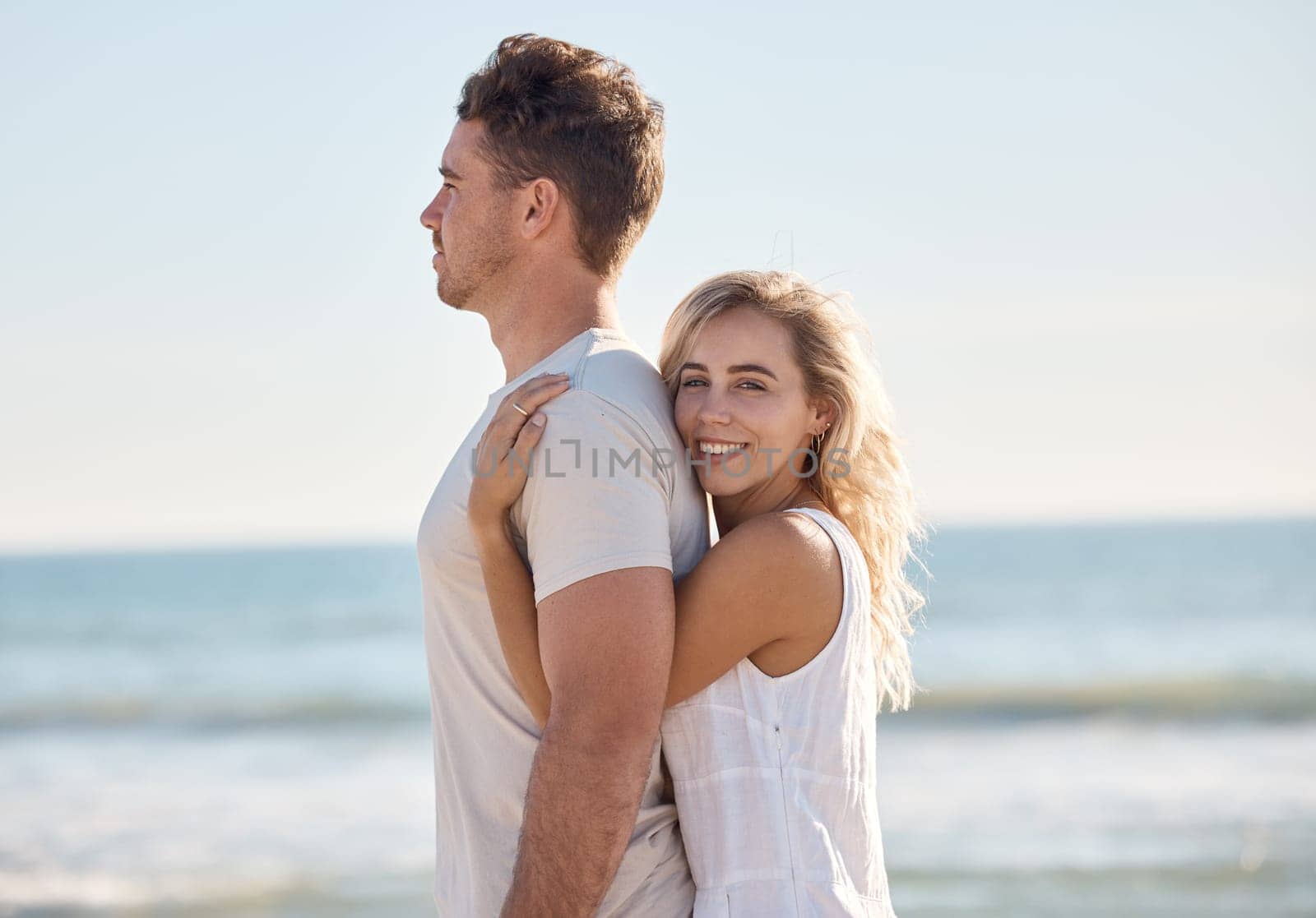 Love, happy and couple hug at a beach in Florida on summer holidays with affection, freedom and peace. Smile, relax and romantic woman enjoys hugging her calm young partner at sea on vacation romance.