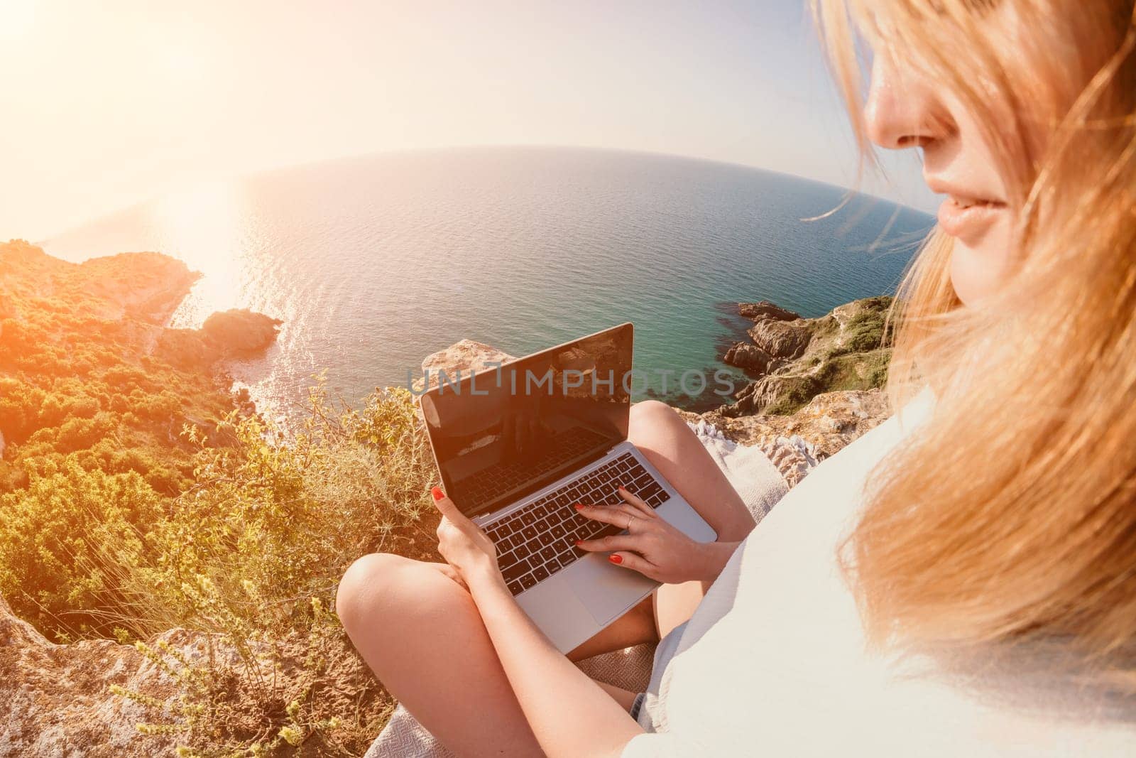 Woman sea laptop. Business woman in yellow hat working on laptop by sea. Close up on hands of pretty lady typing on computer outdoors summer day. Freelance, digital nomad, travel and holidays concept.